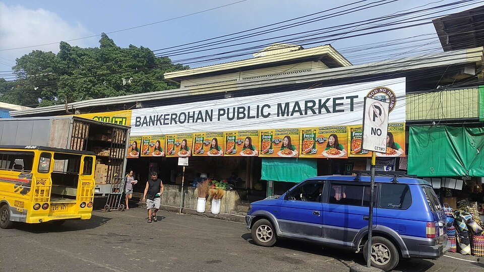 Entrance to Bankerohan Public Market in Davao City, with a yellow jeepney and vehicles outside.