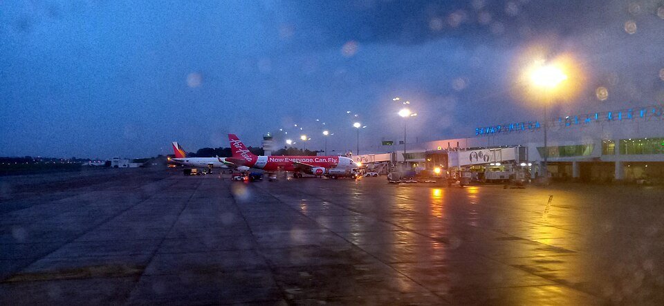 Aircraft parked at Davao International Airport terminal at dusk, with airport lights illuminating the tarmac.