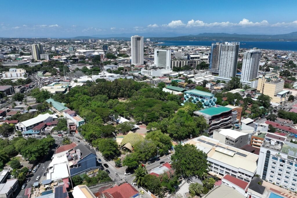Aerial view of Davao People's Park, surrounded by greenery, roads and modern buildings in downtown Davao City, Philippines.