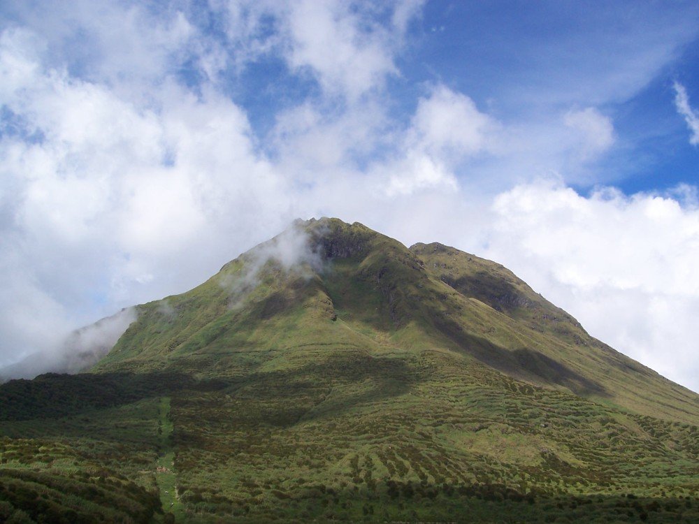 Green slopes and summit of Mount Apo in the Philippines, with clouds drifting across the mountain.