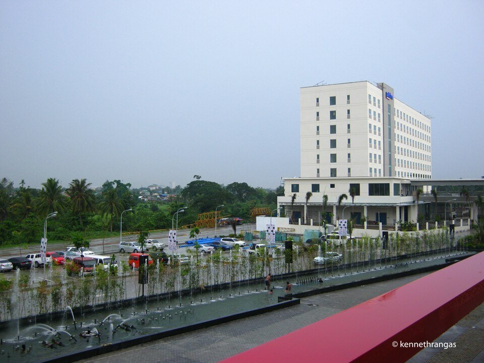 Park Inn by Radisson Davao hotel beside SM Lanang Premier, with a fountain plaza and surrounding buildings.